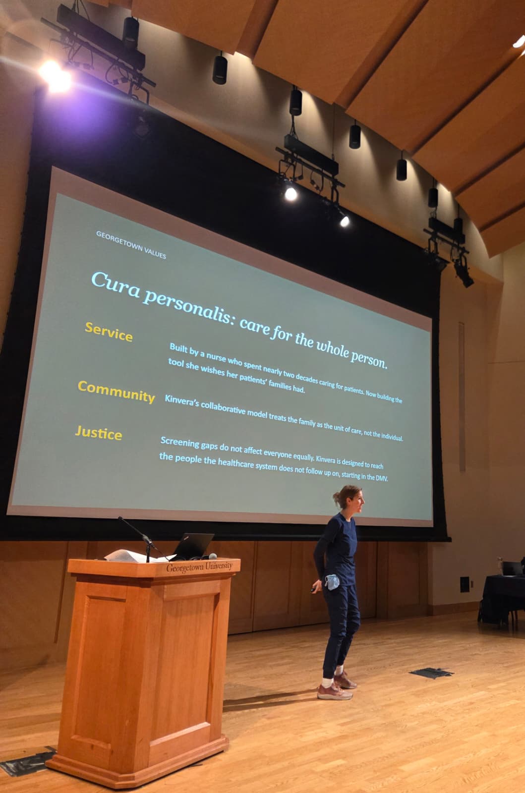Adriana Puram delivering a clinical preventive health seminar at Georgetown, with the Cura personalis slide on screen